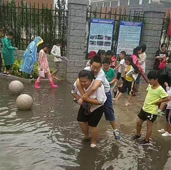 聊城：大雨過后校門口積水，95年女校車管理員背38個孩子上校車